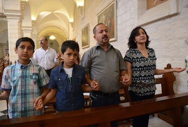 A family prays in 2014 in the Church of St. Catherine in Bethlehem, West Bank. CNS Photo/Debbie Hill