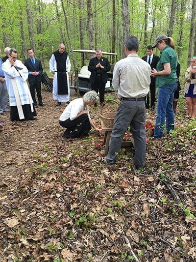 (L-r), Father Tom Zahuta, Brendan Dudley, director of the Respect Life Ministry, Father Augustine Myslinski, OCSO, of the Monastery of the Holy Spirit, and Deacon Norm Keller take part in the interment of Joshua Bishop at Honey Creek Woodlands in Conyers April 12. Friends placed cut flowers at the burial site. Photo By Imelda Richárd