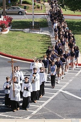 Eighth-grade cross bearer Alex Lambie and a contingent of altar servers lead a procession from St. Catherine of Siena Church to the school gymnasium, as they are immediately followed by Deacon Stephen Ponichtera carrying the monstrance, containing the real presence of Jesus in the Eucharist. The school’s 427 students, faculty, staff, preschool students and parents participated in the Eucharistic procession during the school’s 2016 Faith Rally on the feast of St. Catherine of Siena. Photo By Michael Alexander