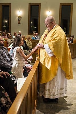 Father Michael McWhorter, pastor of St. Gabriel Church in Fayetteville, shares a moment with Ava Campbell at the Easter Vigil Mass on March 26. Campbell received the sacraments of baptism and Eucharist that evening. Father McWhorter died in his sleep April 29. Photo By Mary Harris 
