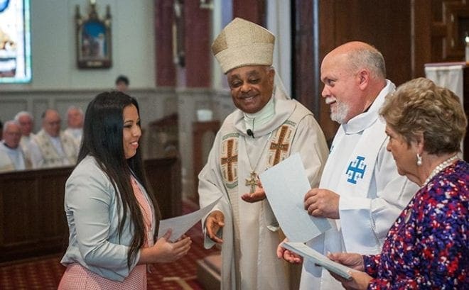 Arianna Ayala, left, Youth of the Year from Corpus Christi Church, Stone Mountain, receives her certificate at the annual Recognition Day Mass from Archbishop Wilton D. Gregory, second from left. Also on hand to congratulate her were Father William Williams, second from right, adviser to the AACCW, and Julie Pardo, AACCW president.