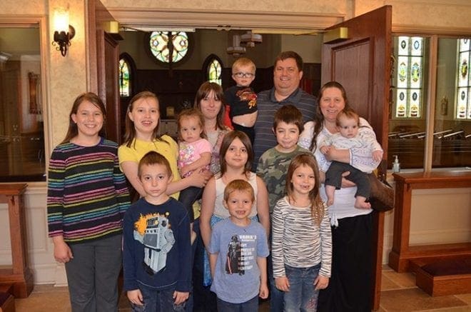 Aimee Miranda, of St. Augustine Church, was the Woman of the Year honoree from her church in Covington. Shown right, holding her youngest, the mother of 11, along with her husband, Jim, finds time to contribute her time for “a lot of little things.” Photo By Cindy Connell Palmer