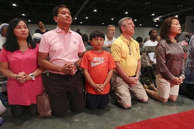 (L-r) Hilda Abrigo, her husband Recto, her 9-year-old son John Paul and Sonny and Frances Fincher kneel facing the altar during the opening Mass of the Eucharistic Congress June 3. The Abrigo family and Finchers worship at Athens’ St. Joseph Church and the University of Georgia Catholic Center, respectively. Photo By Michael Alexander