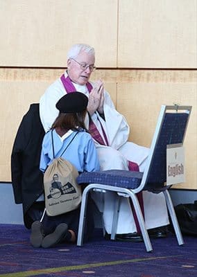 Father James Harrison, pastor of St. Marguerite d'Youville Church, Lawrenceville, hears the confession of a young woman during the Eucharistic Congress. Photo By Michael Alexander