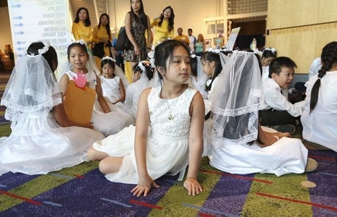 Nine-year-old Kathy Nguyen, foreground center, made her first holy Communion April 17. Here she waits with other first communicants in the north ballroom lobby at the Georgia International Convention Center, College Park, after the ADORE track for children and before the closing Mass. The children lead processions at the Eucharistic Congress. Photo By Michael Alexander