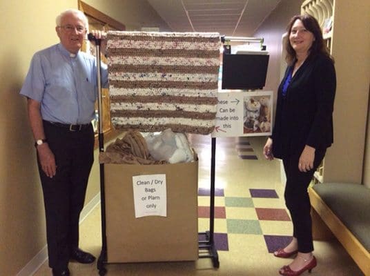 Father Frank Richardson and Karen Blaser of Good Shepherd Church pose at the plastic bag and plarn collection center at Good Shepherd Church. Blaser inaugurated the project in 2016 with the support of the pastor. Photo Courtesy of Good Shepherd Church