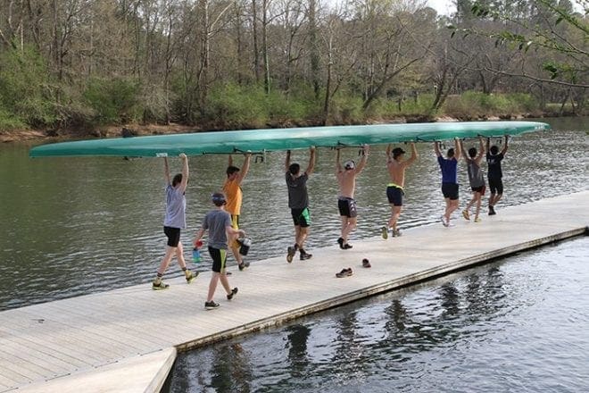 Members of the St. Andrew Rowing Club varsity men’s crew team carry an eight-man boat to the dock on the Chattahoochee River in Roswell. Photo By Michael Alexander