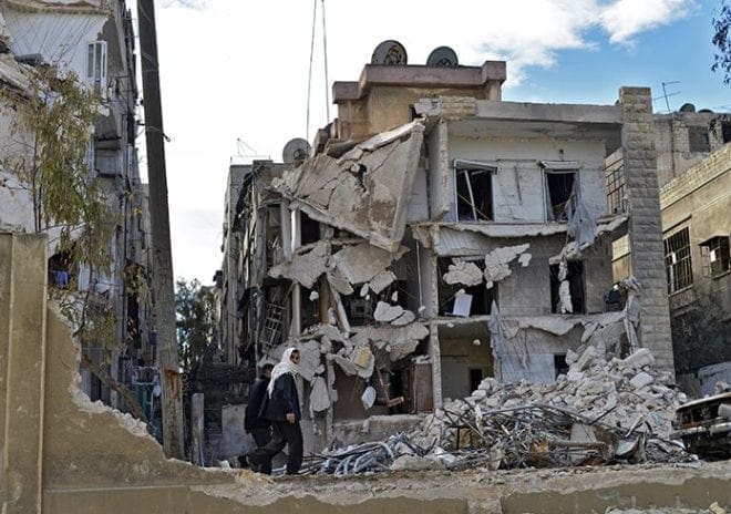 Residents walk past a destroyed building in 2014 after airstrikes in Aleppo, Syria. Christians have been leaving this area because of violence and persecution. Franciscan Father Peter Vasko of the Franciscan Foundation for the Holy Land recently visited Atlanta to talk about his organization’s mission to support the Syrian refugees and to help Christians remain in the Holy Land. CNS Photo/Ali Mustafa, EPA 