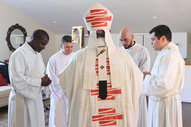 Archbishop Wilton D. Gregory, back to camera, prays with ordination candidates (l-r) Valery Akoh, Roberto Suarez Barbosa, Carlos Cifuentes and Gerardo Ceballos before they walk over to the Cathedral of Christ the King, Atlanta, for the June 25 ordination. Photo By Michael Alexander