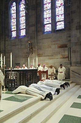 The four ordination candidates to the priesthood prostrate themselves before the altar during the invitation to prayer. Photo By Michael Alexander