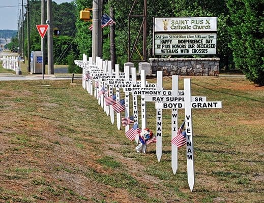 American flags and veterans memorial crosses are set up along Georgia Highway 20 in front of St. Pius X Church, Conyers, on July 4. The project was spearheaded by parishioner Iris Grant, whose husband, Boyd, served in Vietnam. Photo By Lee Depkin