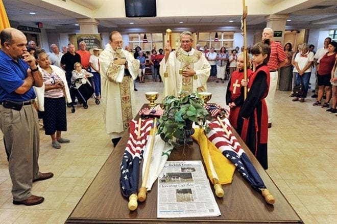 Knights of Columbus Council 10004 donated new American, Georgia, papal and Knights of Columbus flags to the parish. They are blessed in the atrium of the church July 4. Photo By Lee Depkin