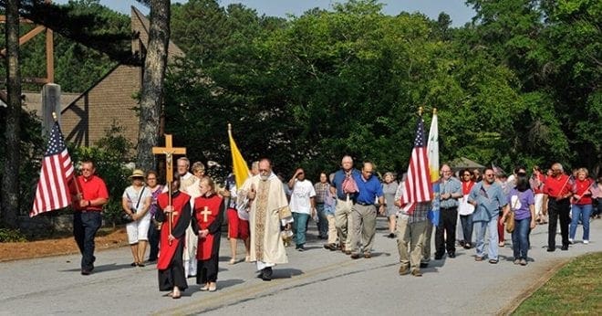 Following the altar server with the processional cross, Father Greg Goolsby, left, pastor, and Deacon Fred Johns, right, lead the congregation from the church after Mass. Father Goolsby blessed the site. Photo By Lee Depkin