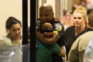 A Dallas police officer is comforted July 7 at Baylor University Hospital's emergency room entrance after a shooting attack. A sniper shot and killed five police officers and wounded seven more at a demonstration in Dallas. CNS photo/Ting Shen, The Dallas Morning News handout via Reuters 