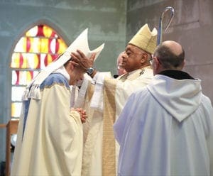 During the presentation of the pontifical insignia, Archbishop Wilton D. Gregory places the miter on the head of the new abbot Augustine Myslinski, OCSO. Photo By Michael Alexander