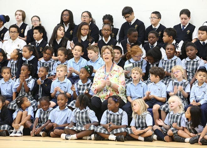 First-grade teacher Leslie McCarthy, center, sits among her students and some second- and sixth-graders during the singing of “Shine, Jesus, Shine.” Photo By Michael Alexander