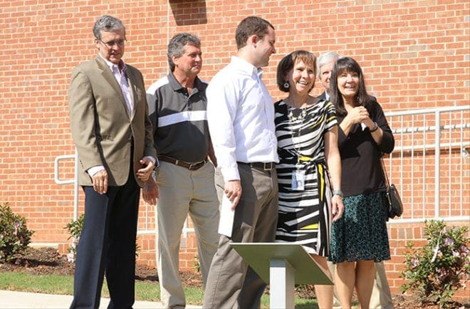 (L-r) Richard Vogtner, his brother and Karen’s husband John, his son Patrick, Karen Vogtner, principal of St. John the Evangelist School, her sister Linda Smith and Linda’s husband Richard all share an emotional moment on the plaza between the Enrichment Center and the fine arts wing, dedicated in memory of Richard and John’s deceased parents, Frank and Betty Vogtner, and Karen and Linda’s deceased parents, Edward and Geneva Ponatoski. The marker, just below them, states that both couples were “founding members of the parish and lifelong supporters of SJE.” Photo By Michael Alexander
