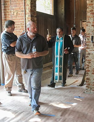 Manuel’s Tavern owner Brian Maloof, foreground, center, the son of the late Manuel Maloof, leads Father John Azar through each part of the bar as it is blessed with holy water. Photo By Michael Alexander