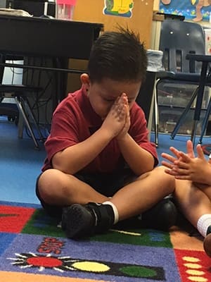 Our Lady of the Assumption School kindergartener Tristan Phouangphet prays for peace on Friday, Sept. 9.