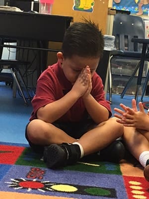 Our Lady of the Assumption School kindergartener Tristan Phouangphet prays for peace on Friday, Sept. 9. 