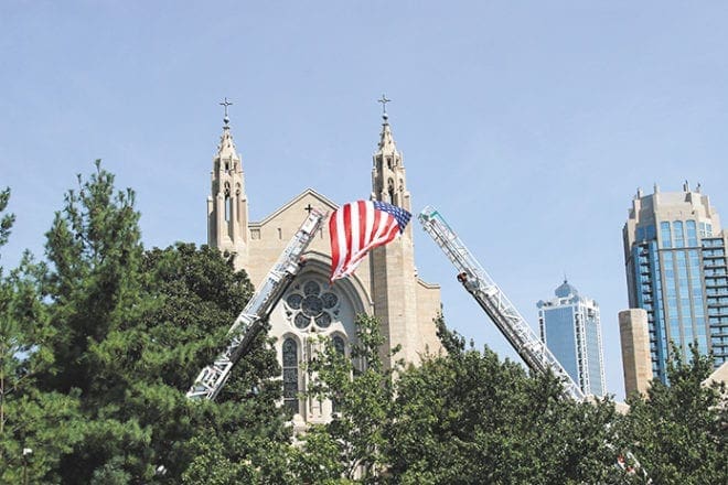 Aerial ladders from Atlanta Fire Rescue companies raise the American flag outside the Cathedral of Christ the King, Atlanta, on Friday, Sept. 9. The Blue Mass was celebrated by Archbishop Wilton D. Gregory for first responders. Photo By David Pace