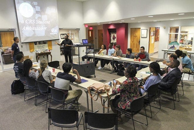 Society of the Divine Word Father Urey P. Mark, standing right, chaplain at Georgia State University and Lyke House, the Catholic Center at the Atlanta University Center, welcomes Michael Trujillo, standing left, Catholic Relief Services relationship manager for the U.S. Southeast Region. Trujillo conducted the Sept. 15 CRS student ambassador training session for Clark Atlanta University, Georgia State University, Emory University and Spelman College students at Lyke House. 