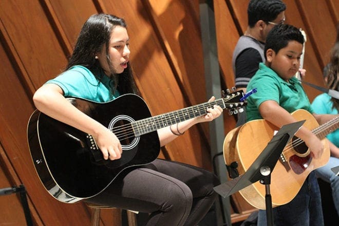 Stephanie Iniguez, 13, and Julio Bello, 10, play with the choir’s guitar section. Both Stephanie and Julio learned how to play the guitar at age nine. Photo By Michael Alexander