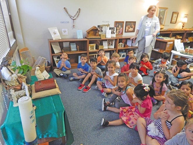 Preschool students at St. John Neumann Church, Lilburn, pray, “open my heart, Lord, help me to love like you,” as they join in the archdiocesan-wide prayer for peace on Friday, Sept. 9. Teacher Alice Hopper, standing, leads the 4-year-old children.