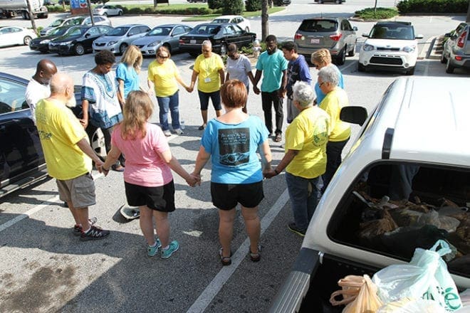 After the vehicles have been loaded and before the volunteers take to the street Aug. 27 to disseminate food to the hungry, the last order of business is a group prayer. Photo By Michael Alexander