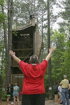Bishop David Talley worked closely with the Disabilities Ministry as its chaplain for more than two decades. In this 2010 photo Msgr. Talley verbally encourages a camper preparing to ride the zip line from its 40-foot platform starting point. For 50 years the Disabilities Ministry, started by Toni Miralles at St. Jude Church, Atlanta, has embraced and supported Catholics with disabilities through its weekend camp ministry. Photo By Michael Alexander