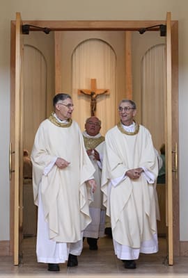 Father Edward O’Connor, right, exits the Holy Cross Church sanctuary with Msgr. Paul Fogarty, left, following the 50th anniversary Mass honoring its founders and former pastors. Father O’Connor, who was the pastor of Holy Cross from 1973 to 1976, was the homilist for the July 26, 2014 liturgy. The two priests were not only former pastors of the parish but fellow Irishmen. Photo By Michael Alexander