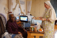Sister Bernadette, a Dominican Sister of Hawthorne, serves lunch to Mary, a patient at Our Lady of Perpetual Help Home. The home, supported solely by voluntary donations from the public, is a free home for those with incurable cancers or other diseases. Photo by Julianna Leopold
