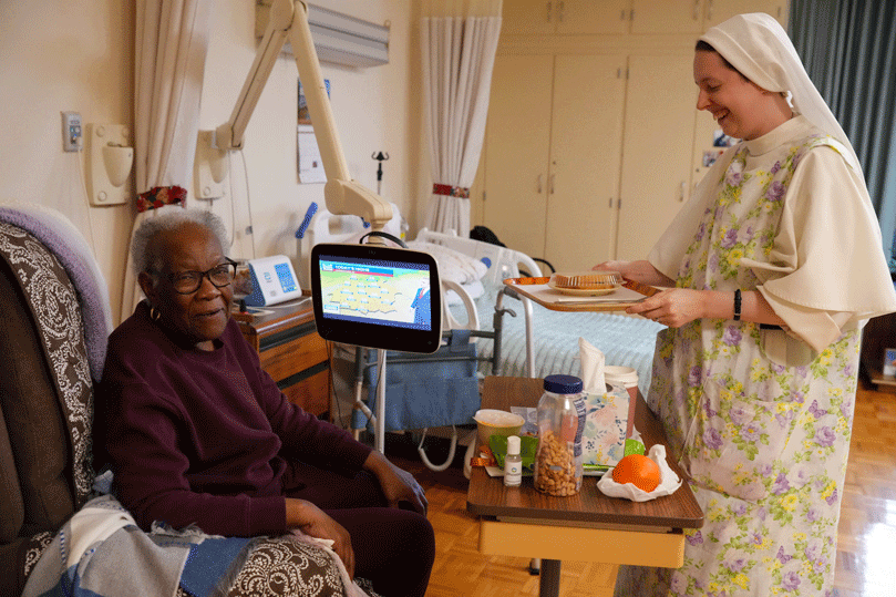 Sister Bernadette, a Dominican Sister of Hawthorne, serves lunch to Mary, a patient at Our Lady of Perpetual Help Home. The home, supported solely by voluntary donations from the public, is a free home 
for those with incurable cancers or other diseases. Photo by Julianna Leopold